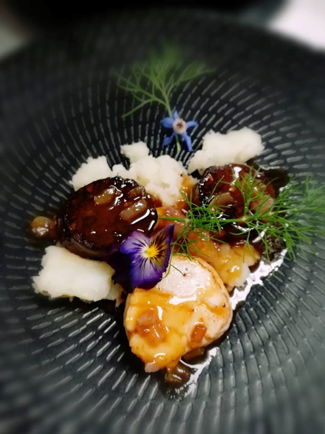 Meat and rice service in a black bowl with a small flower.