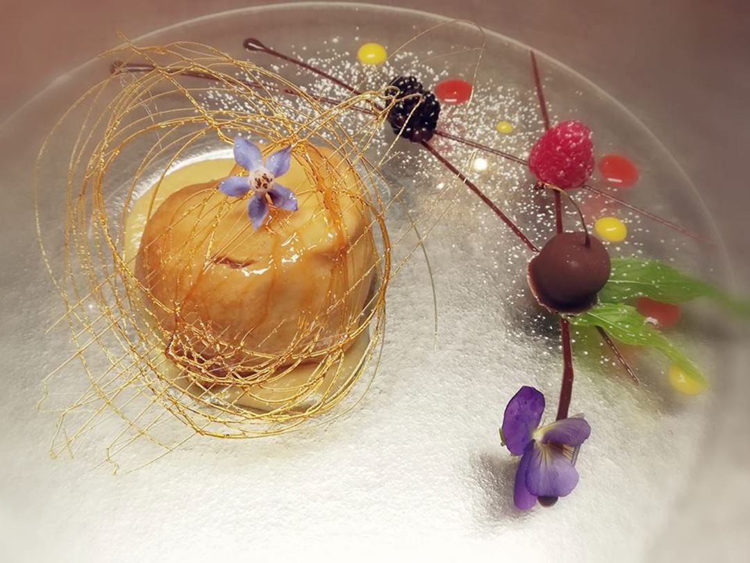 Apple crepe with caramel sauce served in a clear glass plate.